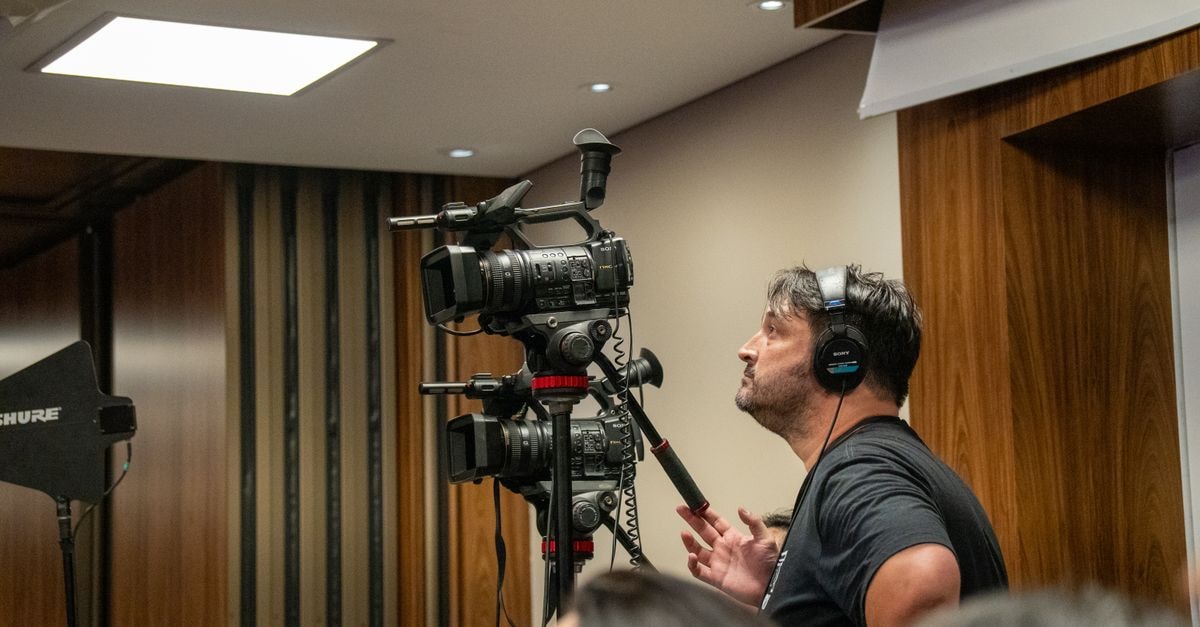 Brewers' Chourio reaches 20-homer mark as Milwaukee tops Rangers 5-3 Cameraman operating professional video cameras during an indoor event. Perfect for media and broadcasting themes.