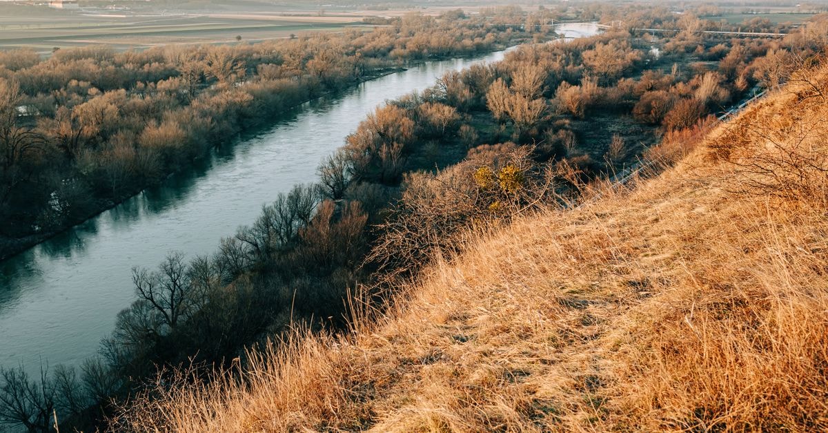 Aerial view of a peaceful autumn landscape featuring a winding river through rural fields at sunset.