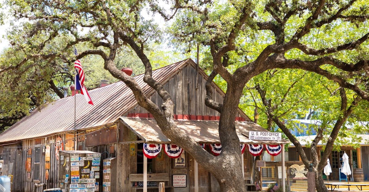 Texas Roadhouse at $212.67: Comfortable Operations, Uncomfortable Price Rustic wooden post office in Luckenbach, Texas, with American flag and oak tree.