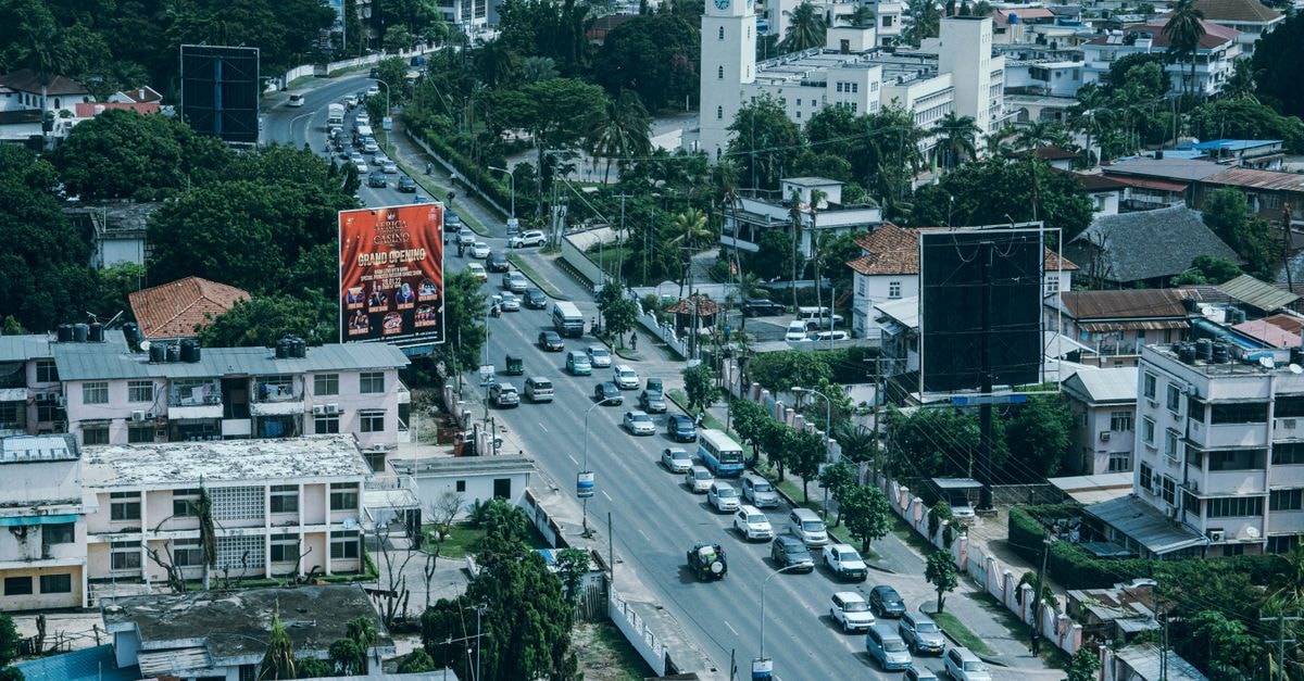 Royal Grand Hotel in Monrovia: Coastal Cape Mesurado Stay Drone shot capturing busy street and lush greenery with cityscape.