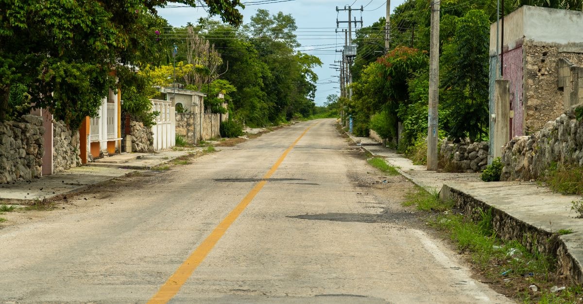 Hotel Rosa del Alba in Chetumal: Calm Stay Near the Maya Museum Quiet rural street in Suma, Yucatán, surrounded by lush greenery and rustic architecture.