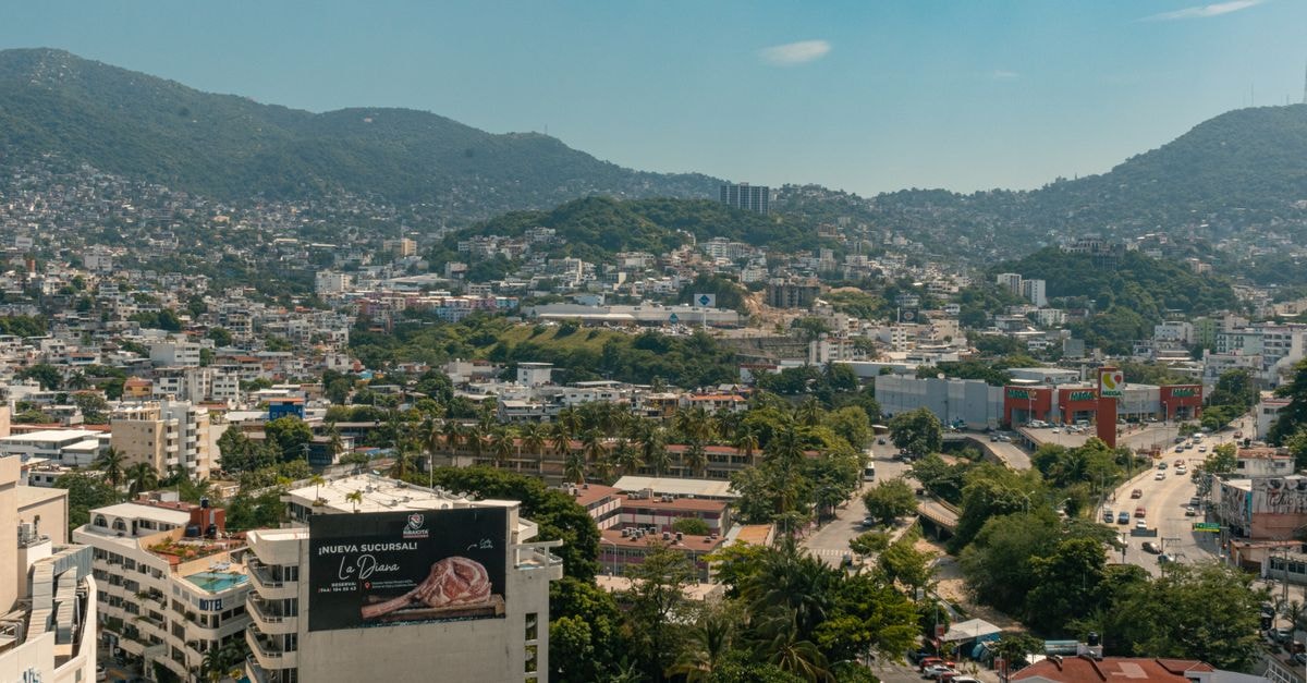 De la Costa Hotel in Encarnación: Riverside Stays on Avenida Rodríguez de Francia A breathtaking aerial view of Acapulco with lush hills and urban landscape under a clear blue sky.