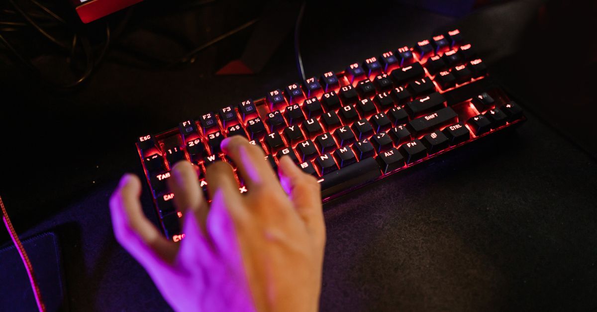Moonshot's Kimi K3 Set for Open-Weights Release on July 27 as UK-US Cyber Tests Trail US Models A hand engaging with a glowing mechanical gaming keyboard in a dark setting.