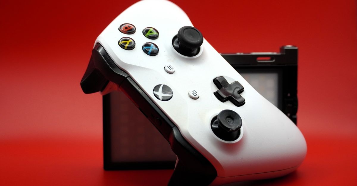 Valve 將 SteamOS 測試版擴展至 MSI 與 OneXPlayer 掌上型遊戲機 白色遊戲控制器特寫,黑色按鈕襯托於鮮紅色背景前。