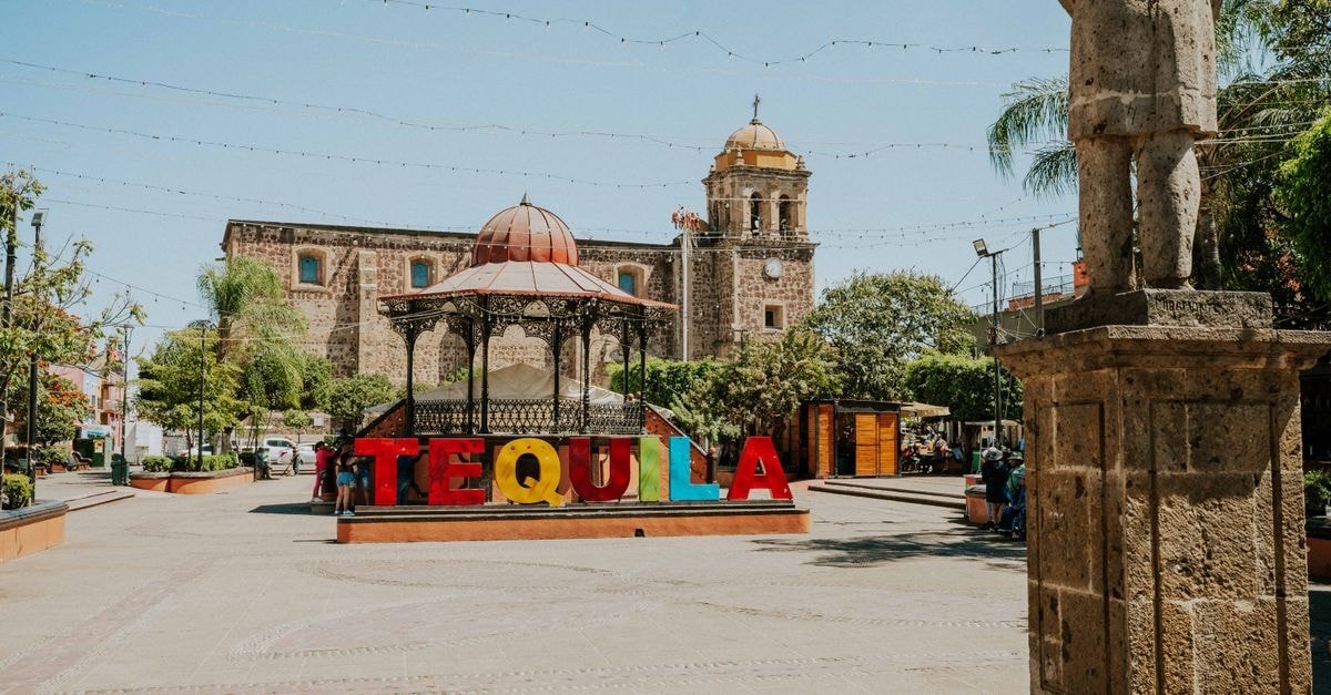 Vibrant Tequila sign in sunny Mexican plaza with historic architecture.