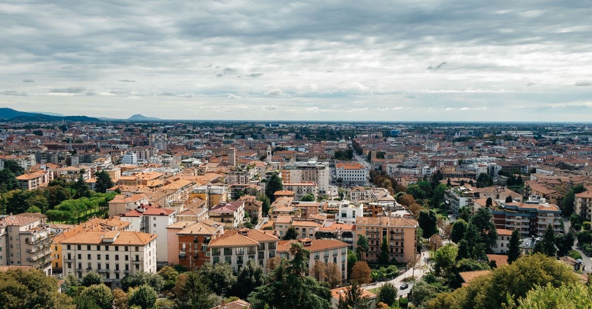 Aerial view of Bergamo cityscape in Lombardy, Italy showcasing urban architecture and greenery under a cloudy sky.
