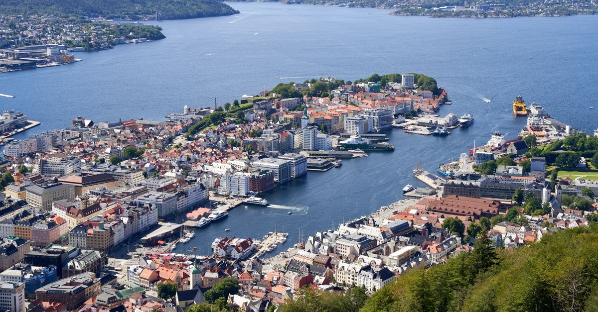 A breathtaking aerial view of Bergen's cityscape with its bustling harbor, surrounded by fjords.