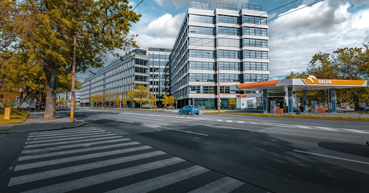 Clean Energy Fuels: Cheap on the Tape, Fragile on the Cash Flow A vibrant cityscape featuring a modern office building and gas station under a blue sky.