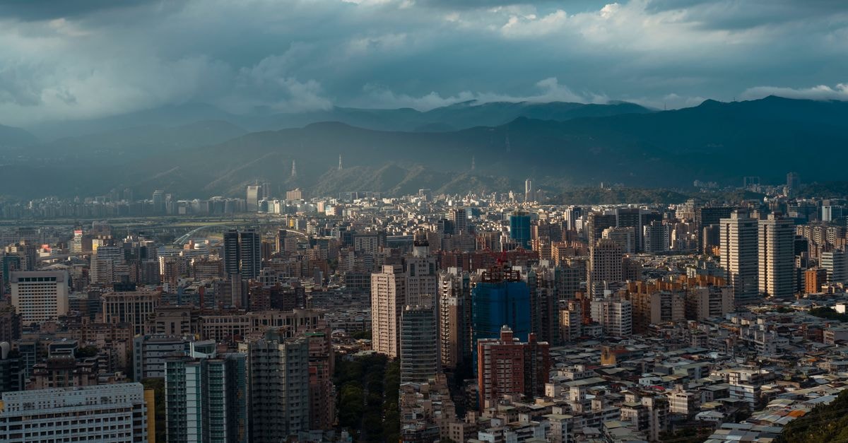 Railway Hotel, Fuyang: A Practical Stay on Xiangyang Road Dynamic urban cityscape surrounded by mountains under a dramatic cloudy sky offering an aerial perspective of the bustling city.