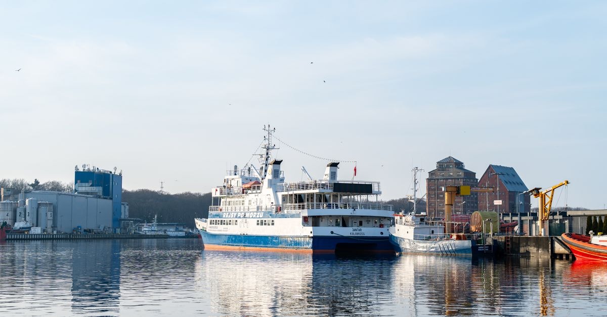 Slow Days in Gdynia: A Travel Guide to Poland's Baltic Port A ferry docked at the industrial port of Kołobrzeg, Poland, with a clear blue sky.