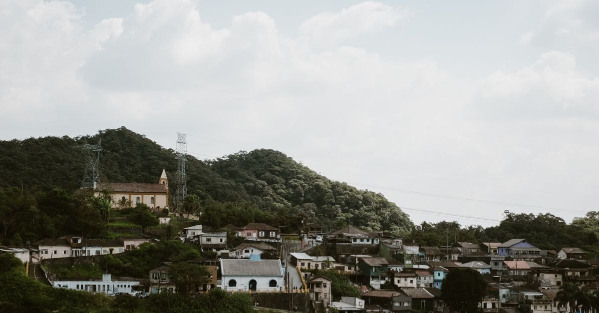 Picturesque village on a hillside with a prominent church surrounded by lush greenery under a cloudy sky.