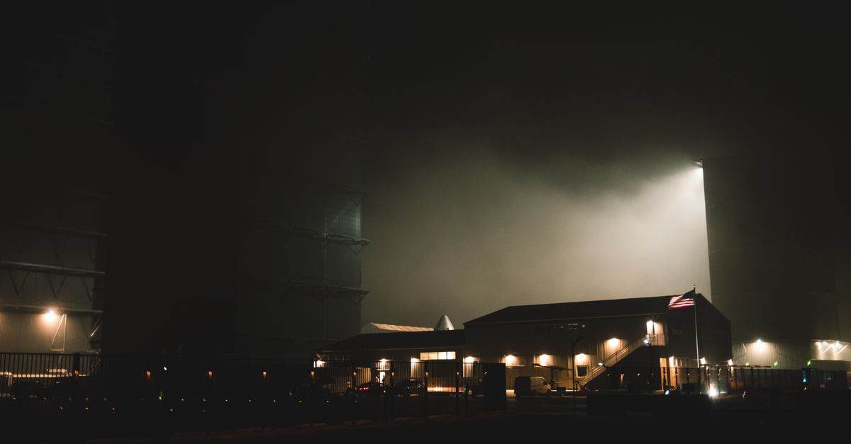 SpaceX Prepares First Post-IPO Earnings as Louisiana Spaceport Deal Advances and Starship Reentry Survives A dramatic nighttime view of an industrial facility at a space exploration center with atmospheric lighting.