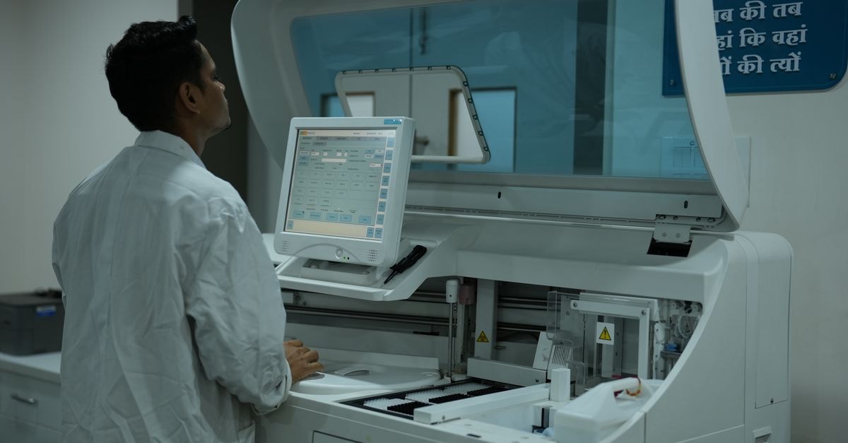Novartis India to buy Pfizer's Minipress trademarks for ₹1,250 crore A lab technician operates a clinical analyzer in a modern laboratory setting.