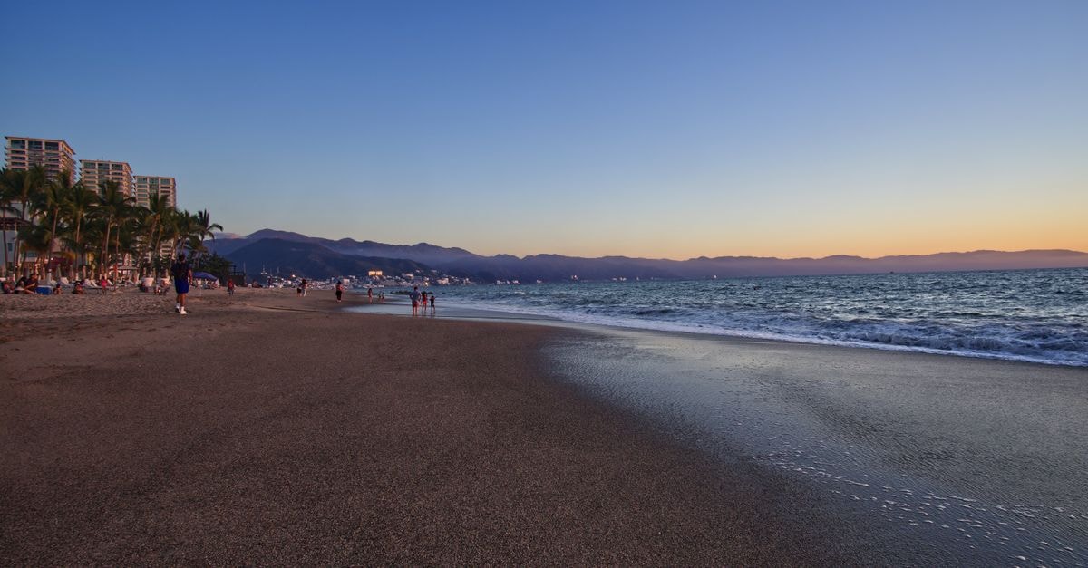 Beautiful sunset over a tropical beach in Puerto Vallarta, Mexico, with gentle waves and vibrant sky.