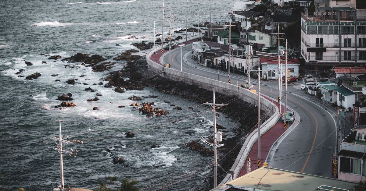 Tongyeong Travel Guide: A Slow Weekend on Korea's Southern Coast Aerial view of a coastal road and town in Gangneung, South Korea, showcasing seaside urban landscape.