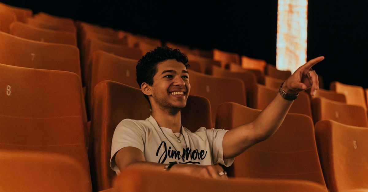 'Spider-Man: Brand New Day' Tracking for One of the Biggest Global Openings Ever A young man with short hair smiles and points while seated in an empty cinema.