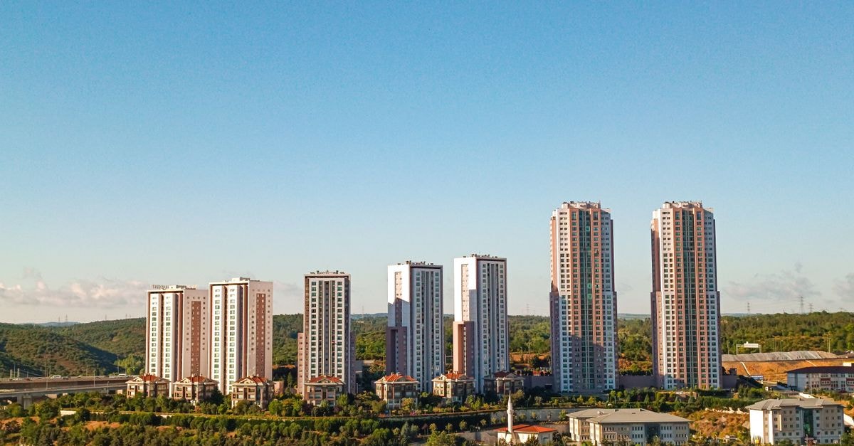 Aerial view of urban skyscrapers surrounded by greenery on a bright, clear day.