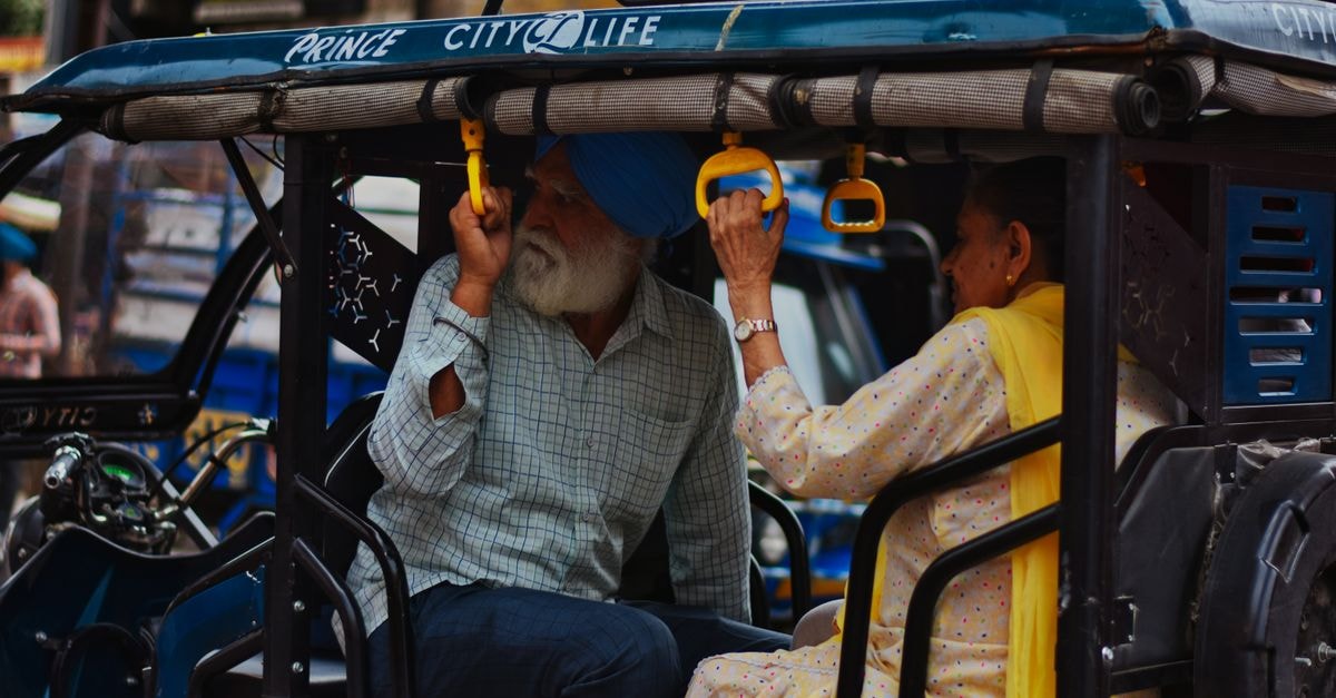 HKJ Residency, Amritsar — A Quiet Lane Near the Golden Temple An elderly couple in traditional attire enjoying a ride in an auto rickshaw on the bustling streets of Amritsar, India.