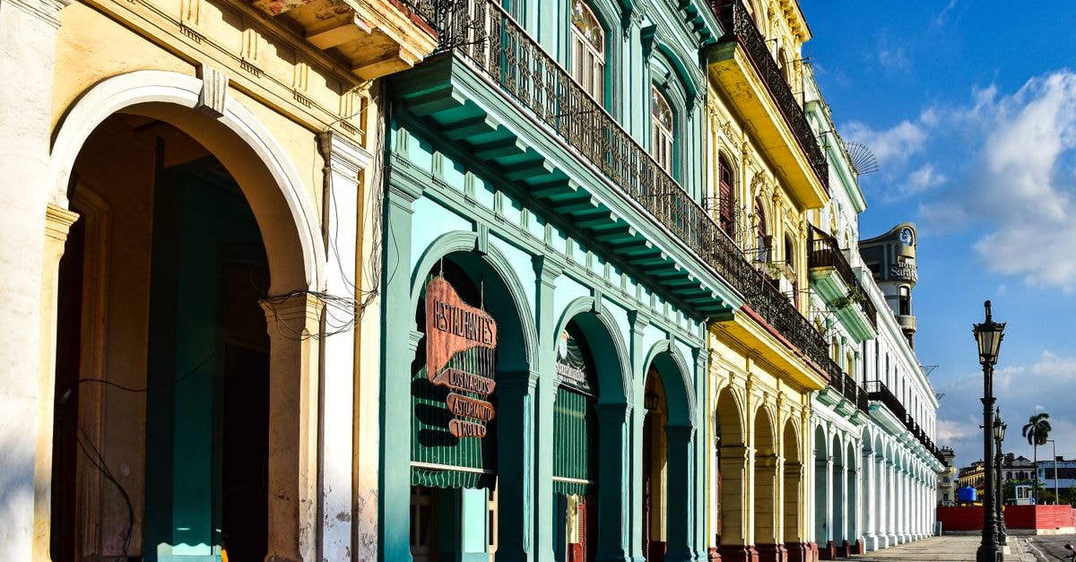 Vibrant colonial buildings with arches lining a sunny street in Havana, Cuba.