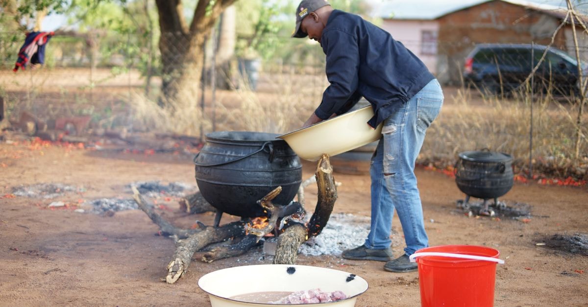 A man prepares food in cauldrons over a fire in Gaborone, Botswana.