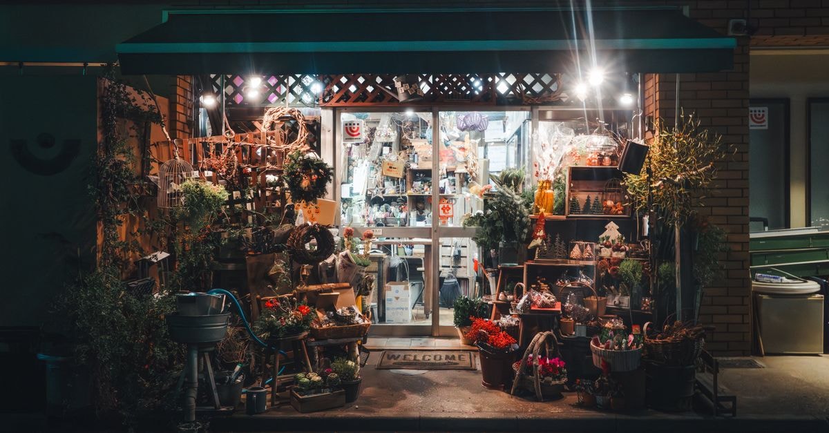 Olsztyn Travel Guide: Lakes, Quiet Streets, and Warm Welcome Warmly lit flower shop entrance adorned with various plants and decorations at night.