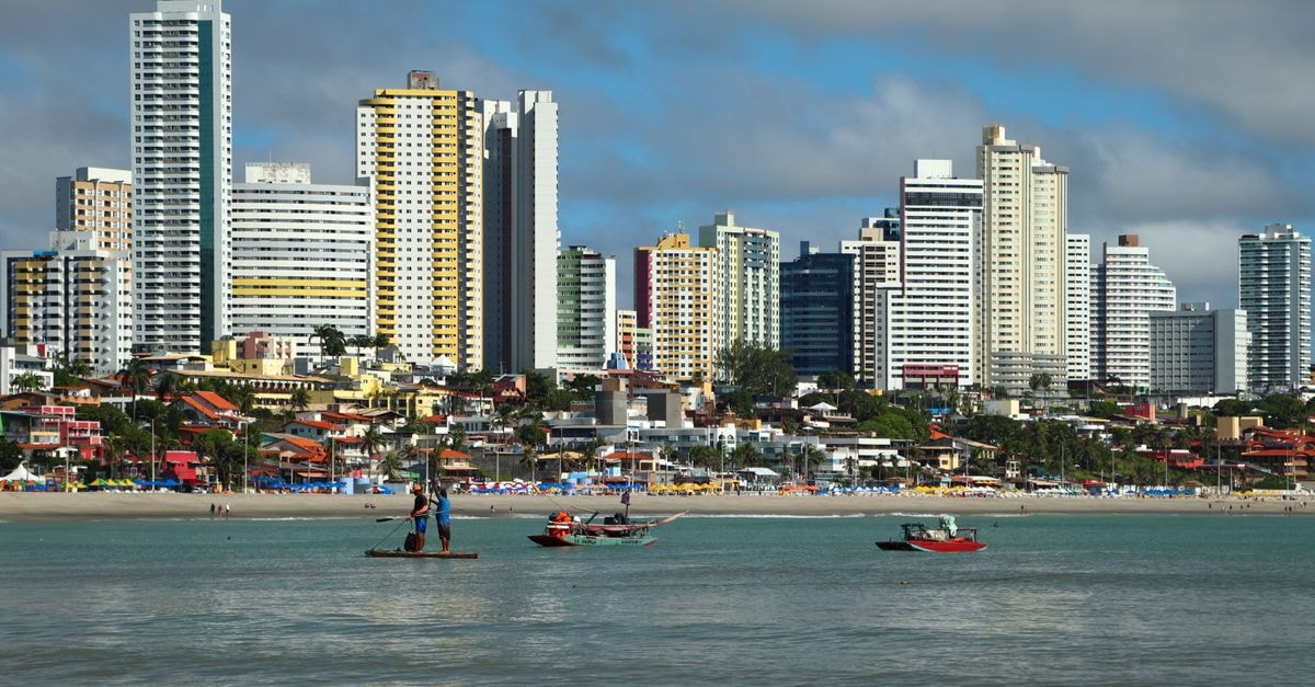 Vibrant skyline of Natal, Brazil with fishermen at the beach. Captivating seascape with tall buildings.