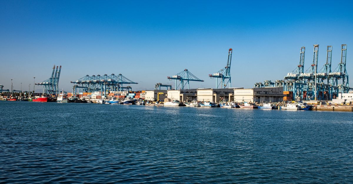 Portsmouth Travel Guide: Coastal Charm Beyond the Dockyard A bustling harbor with large cranes, cargo containers, and ships under a clear blue sky.