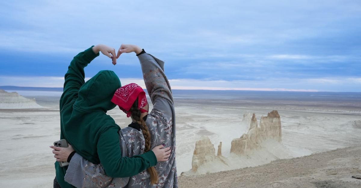 Two people create a heart shape with their hands overlooking the Aktau desert in Kazakhstan.