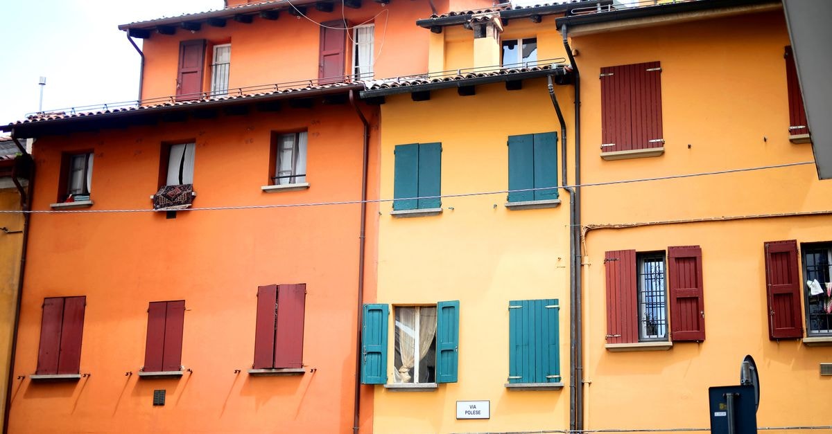 Vibrant orange and yellow buildings line a street in Bologna, showcasing classic Italian architecture.