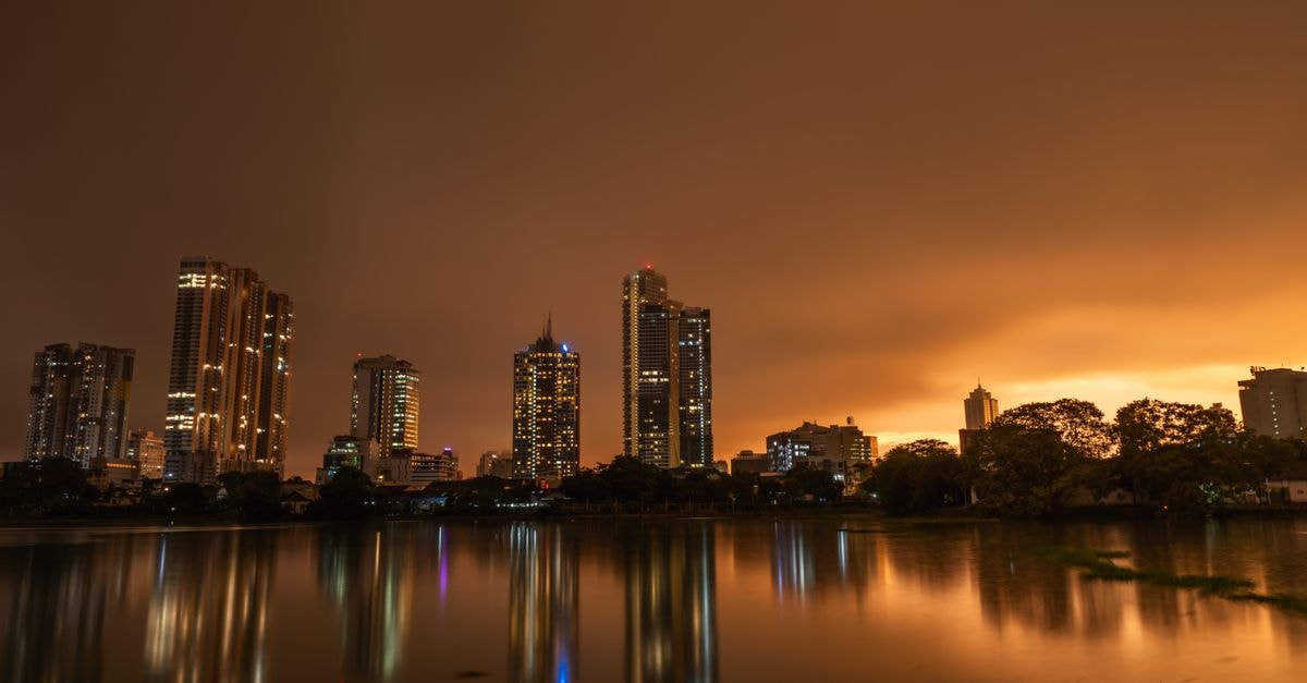 Hilton Colombo in Sri Lanka: CBD Stay Linked to the World Trade Centre Dramatic twilight skyline of Colombo, Sri Lanka with city lights reflected on calm lake waters.
