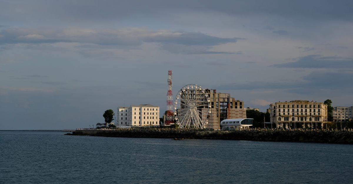 Grand Way in Sochi: A Compact Stay on Severnaya Street Urban skyline with Ferris wheel beside the sea during daytime under cloudy sky.