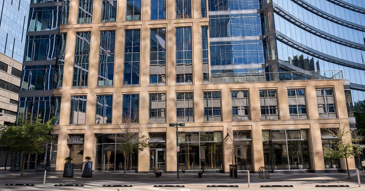 Waymo opens Dallas robotaxi service to all riders Contemporary urban architecture featuring a sleek office building with glass facades and reflections.