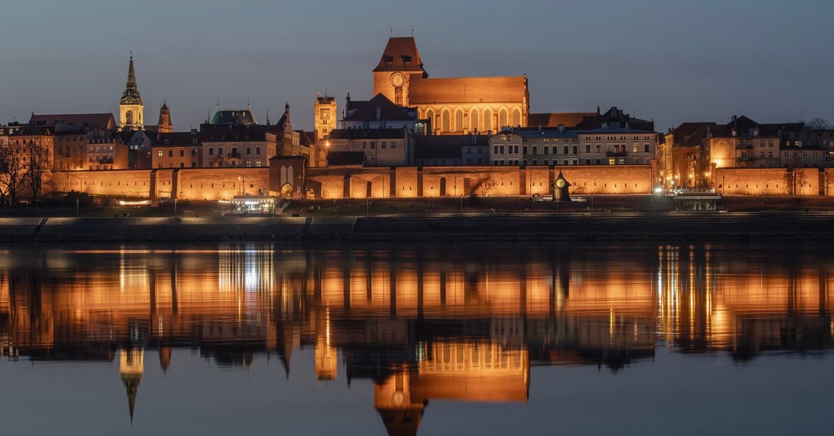 Ibis Budget Toruń, Toruń — Smart Pick by the Old Town Experience the illuminated beauty of Toruń's medieval architecture reflecting on the river at night.