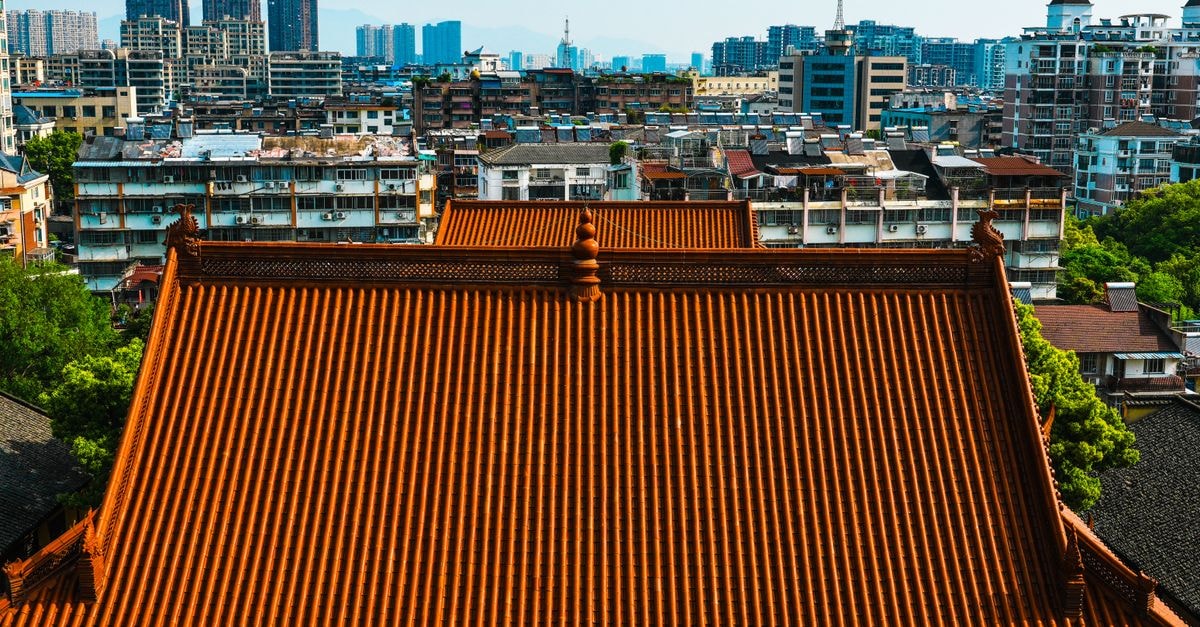 Luzhou Travel Guide: Yangtze River Views, Old Distilleries and Sichuan Flavor A traditional Chinese temple roof contrasts with a modern urban skyline, showcasing a blend of old and new architecture.