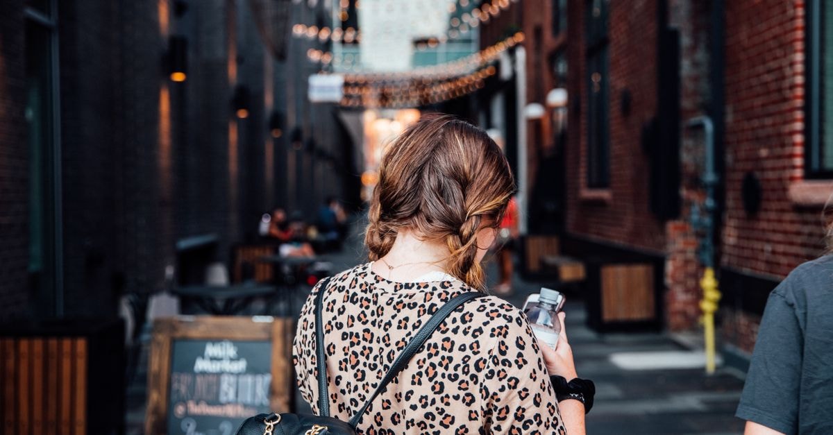 An Omaha Travel Guide for First-Time Visitors Back view of a woman with braided hair strolling through a lively alley in Denver, CO.