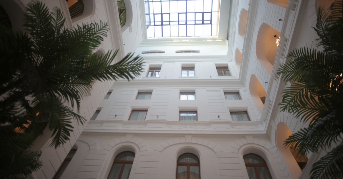 Capture of a sophisticated indoor atrium featuring a glass skylight and lush palm trees for a serene setting.
