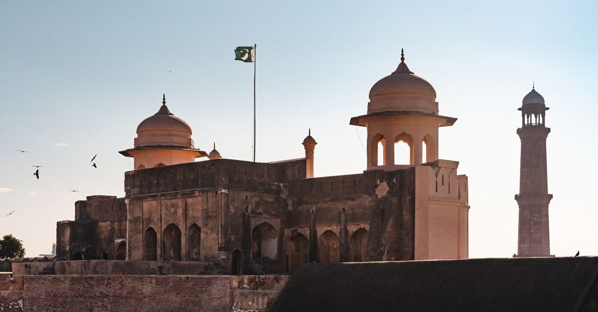 Four Points by Sheraton Lahore: Marriott's First Pakistan Debut A view of Lahore Fort with a minaret silhouette against a vibrant sunset sky, featuring the Pakistani flag.