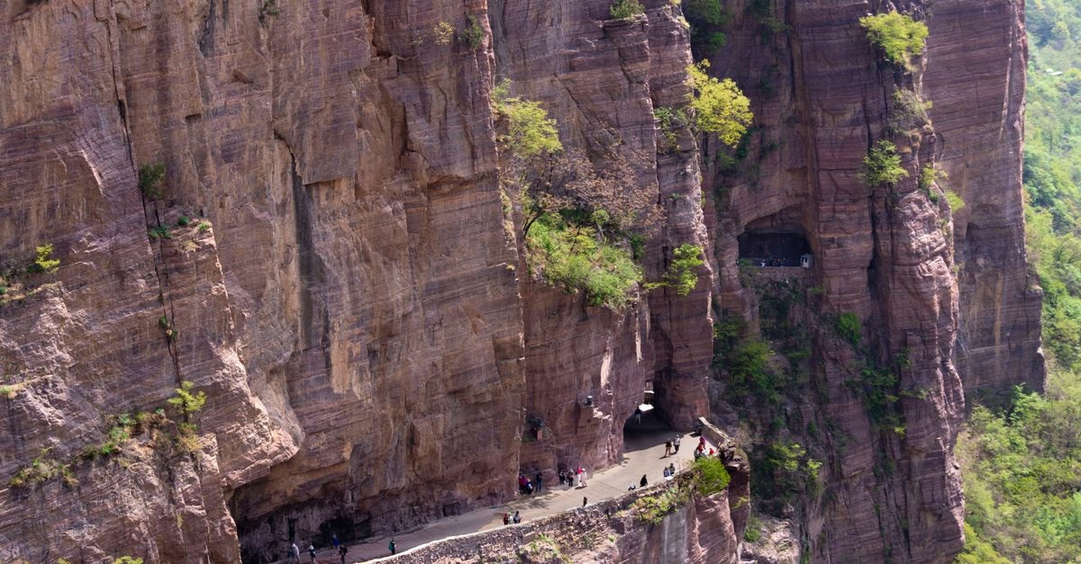 Explore the dramatic cliffs and winding Guoliang Tunnel Road in Xinxiang, China, carved into a mountain face.
