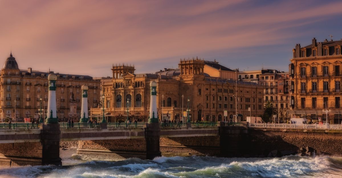 Loinaz, San Sebastián: A Pintxos-Friendly Stay in the Old Town Charming view of a bridge and historic architecture in San Sebastián during sunset.