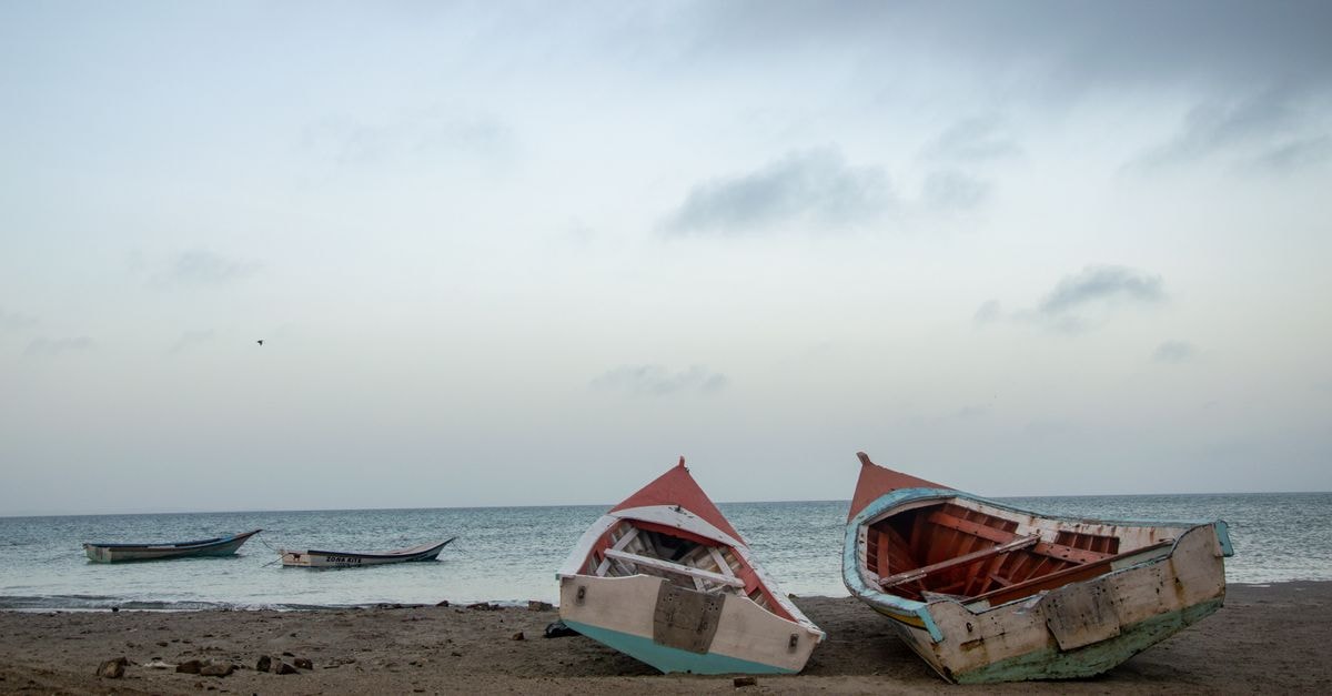 Rustic boats moored on a tranquil sandy beach with calm ocean view.