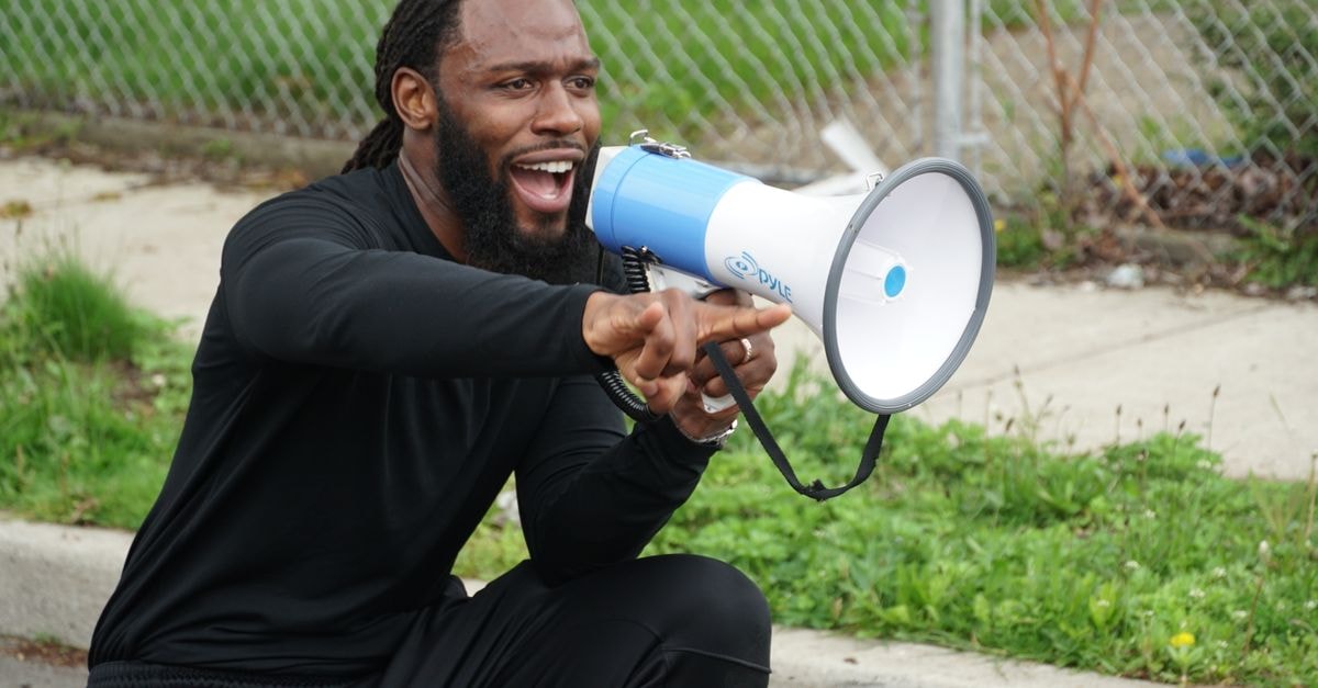 Energetic man using a megaphone to engage audience outdoors, New York.