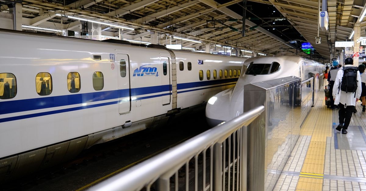 Shinkansen bullet train at a busy Tokyo station platform with passengers boarding.