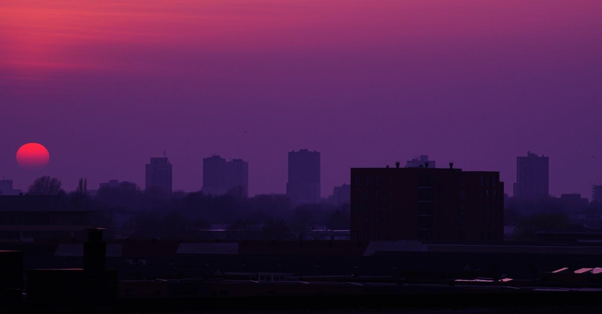 夕陽下的城市天際線剪影，呈現戲劇性的紫橙色天空。