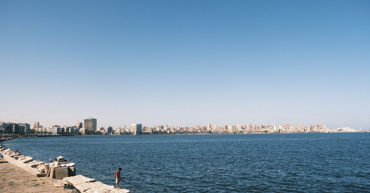 Tibesti Hotel in Benghazi: Harbour-View High-Rise on 23rd July Lake Serene view of Alexandria's coastline with cityscape in the background under a clear sky.