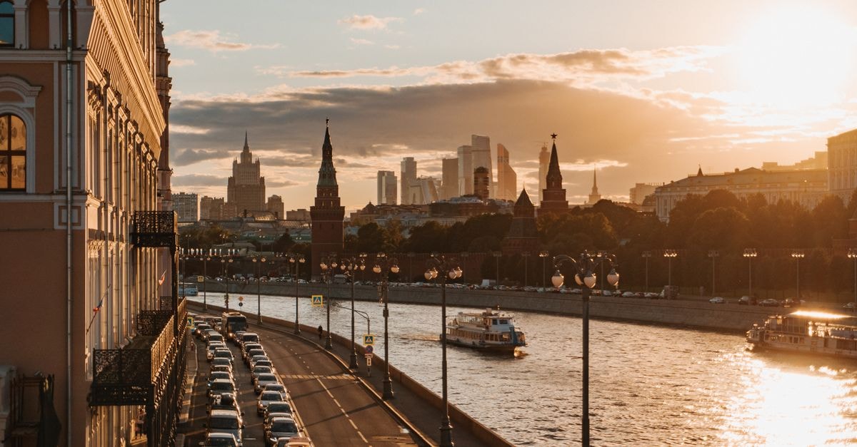 Moscow Travel Guide: Getting Around, Sights, and Food Golden sunset over Moscow's river with the Kremlin and skyscrapers in view.