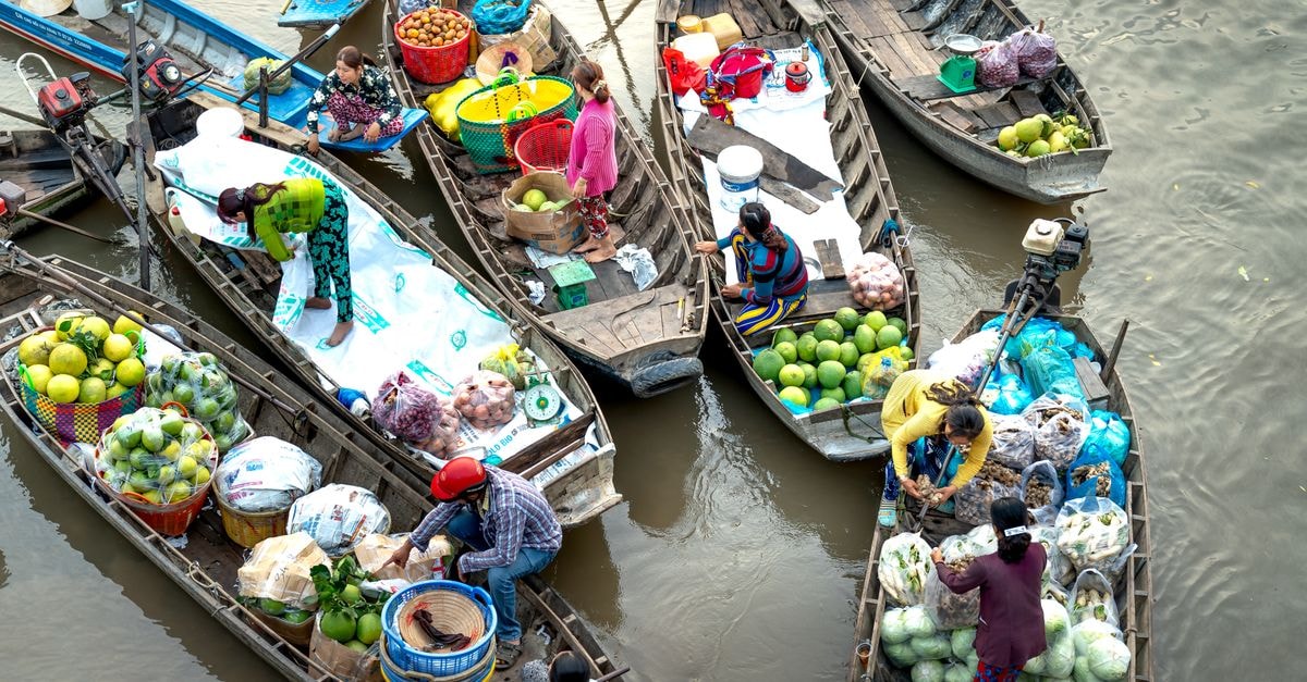 Banjarmasin travel guide: rivers, floating markets, and Banjar charm Colorful scene at an Asian floating market with boats filled with fresh fruits and vegetables.