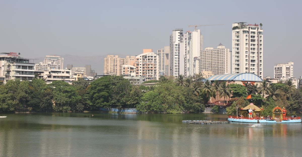 Virar Travel Guide: A Slow Look at a Mumbai Suburb Serene view of a city lake with high-rise buildings and seagulls.