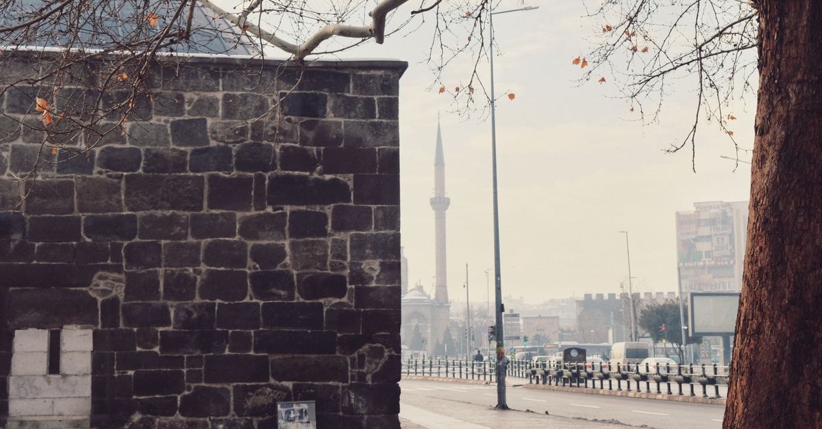 Old stone building with a mosque minaret in the background on a winter day.
