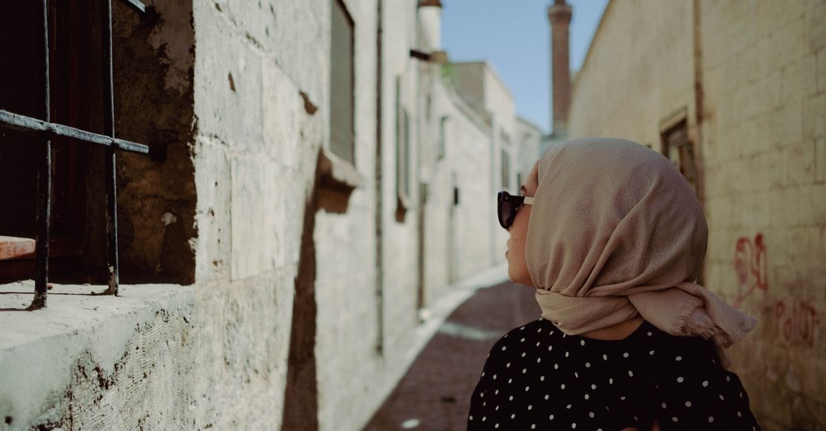 Hilton Garden Inn Sanliurfa in Sanliurfa: A Modern Stay Near the Historic Center Woman in headscarf exploring the historic streets of Şanlıurfa under a clear sky.