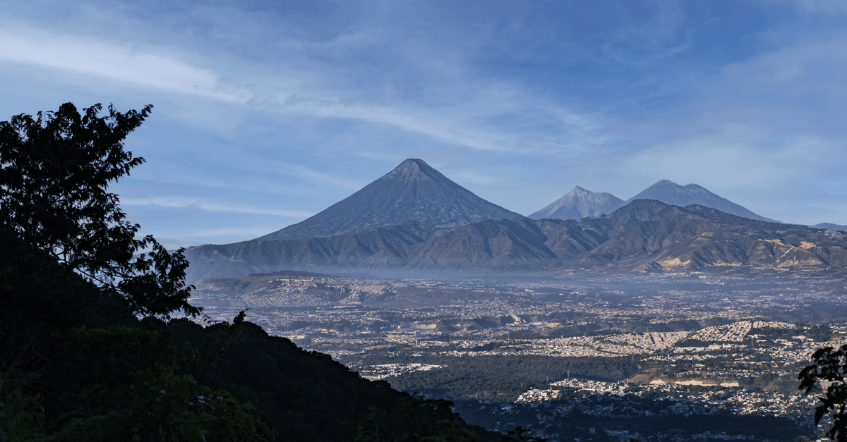 Stunning landscape of Guatemala's volcanic peaks under a vibrant blue sky, capturing lush nature.